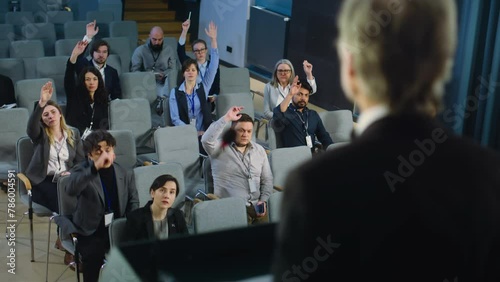 Back view of politician or businessman pronouncing political speech, giving interview for television or media. Journalists raise hands and ask questions during press campaign in the conference hall. photo