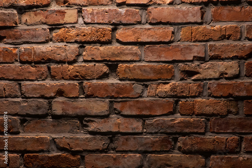 A relief wall made of old red brick is illuminated from above. Background. Texture.