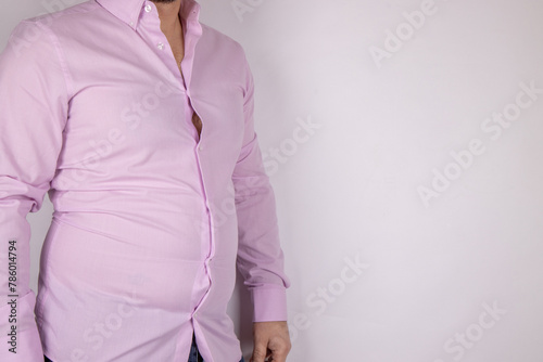 A middle aged slightly over weight man in a pink shirt that is now too small due to the man putting on weight and needed to go on a diet, time for a diet concept.