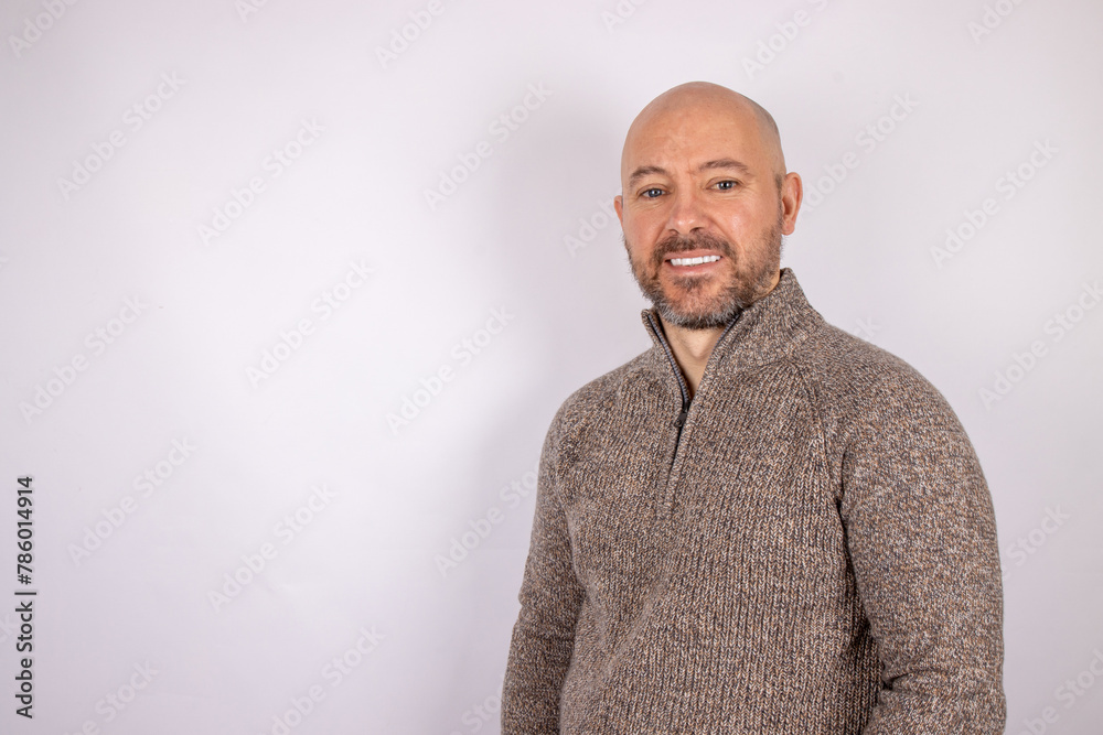 Fototapeta premium A middle aged bald shaven headed man with a beard smiling wearing a jumper on white background