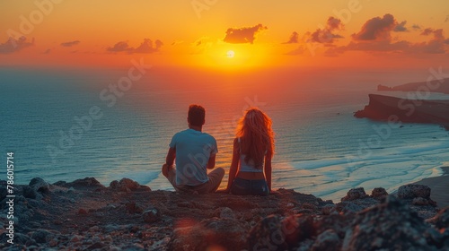 Young couple sits together on a rocky hill, watching a breathtaking sunset over the ocean. The scene captures a moment of tranquility and companionship.