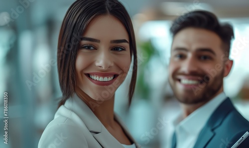 Young smiling diverse cheerful businesswoman and businessman standing close discussing working tasks with tablet during the conference meeting in light contemporary office building smiling at camera