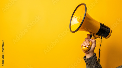 Hand holding megaphone on yellow background. Hiring ad