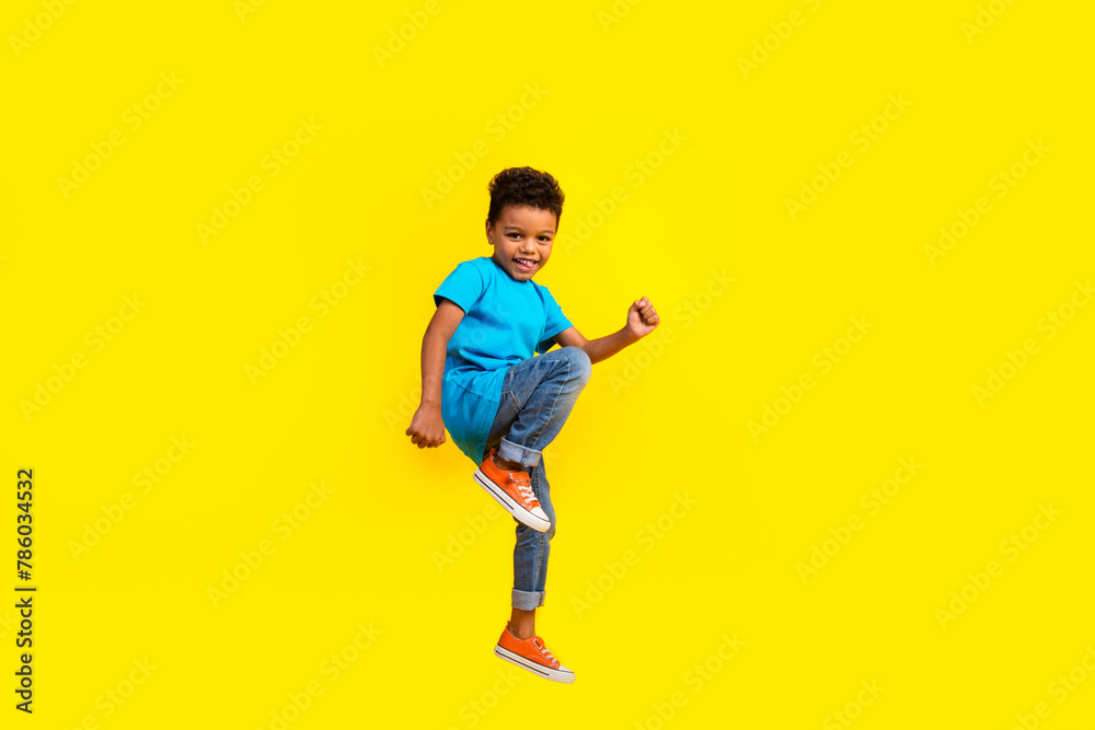 Full body photo of good mood nice small child dressed blue t-shirt jeans flying on black friday isolated on vibrant yellow background