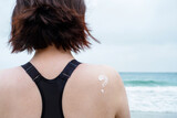 Smear of sunscreen on female shoulder against backdrop of the sea.