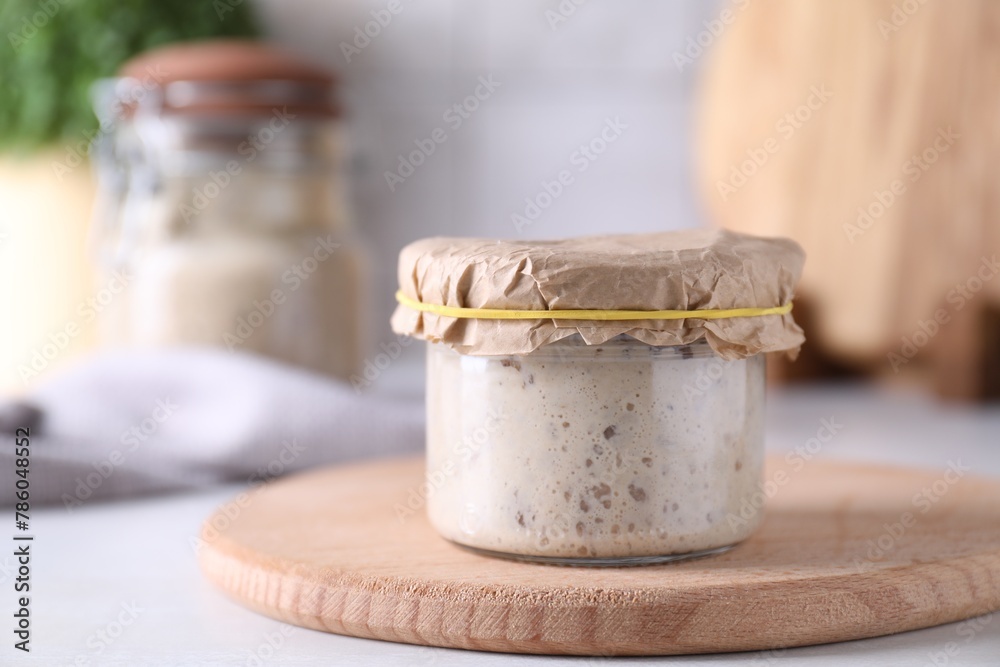 Sourdough starter in glass jar on table, closeup. Space for text Sourdough starter in glass jar on table, closeup. Space for text