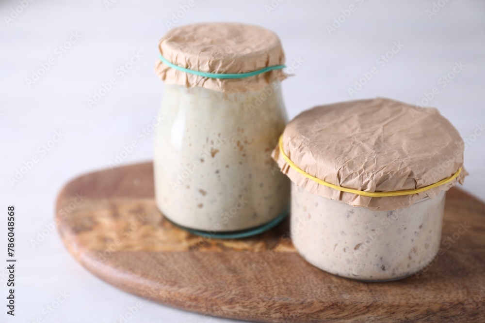 Sourdough starter in glass jars on light table, closeup