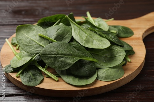 Bowl with fresh spinach leaves on wooden table, closeup