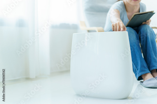 Asian woman using air purifier during living at home.