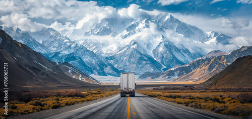 A truck is driving down a road in front of a mountain range #786065731