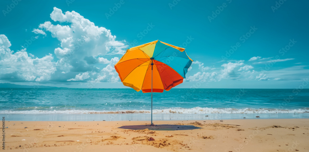 A colorful umbrella is sitting on the beach, providing shade from the sun