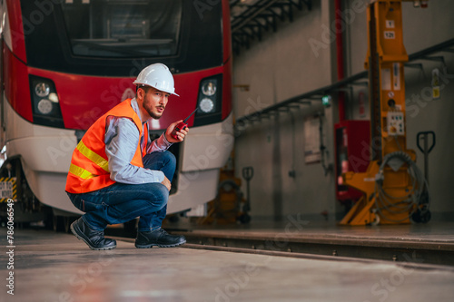 The engineer is captured in the dynamic environment of a train and railway garage, immersed in the meticulous tasks of maintenance, repair, or inspection. 