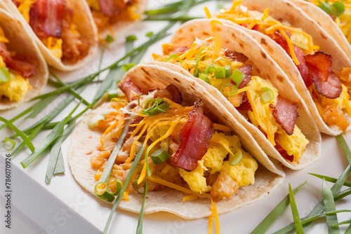 Breakfast tacos with hashbrowns, scrambled eggs and bacon topped with cheese and green onion