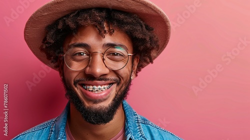 Advertisement for dental care featuring a comical curly-haired man wearing metal braces and glasses, showcasing his bright smile against a pink backdrop. photo