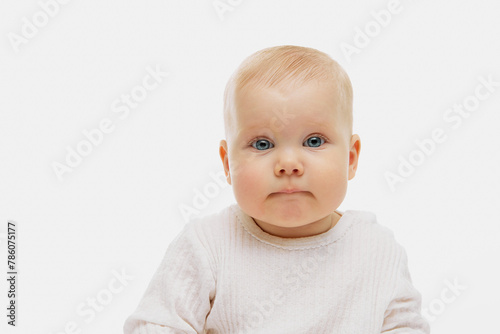 Portrait of cute, charming little baby, kid in dressed in white clothes looking at camera against white studio background. Concept of childhood, motherhood, life, birth. Copy space for ad