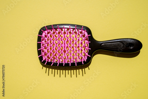 Top view of a hair brush on a vibrant yellow surface, showcasing neon pink and black colors with lattice pattern. Ideal for product photography, beauty concepts, and fashion accessories promotions