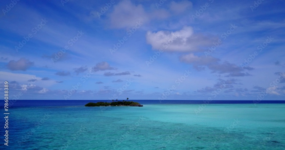 Small tropical island at a distance surrounded by blue and turquoise ocean water in Asia