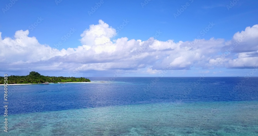 Aerial scenic view of a calm blue seascape and a coast with lush nature on a sunny day in Indonesia