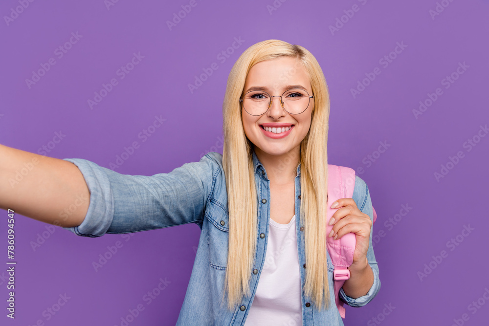 Self-portrait of attractive cheerful intelligent girl going back to school isolated over bright violet purple color background Self-portrait of attractive cheerful intelligent girl going back to school isolated over bright violet purple color background