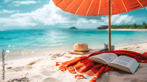 Beach umbrella with a beach towel and book. Copy space.