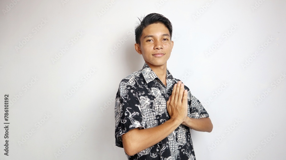 Excited handsome young Asian man dressed in batik with greeting gesture Excited handsome young Asian man dressed in batik with greeting gesture