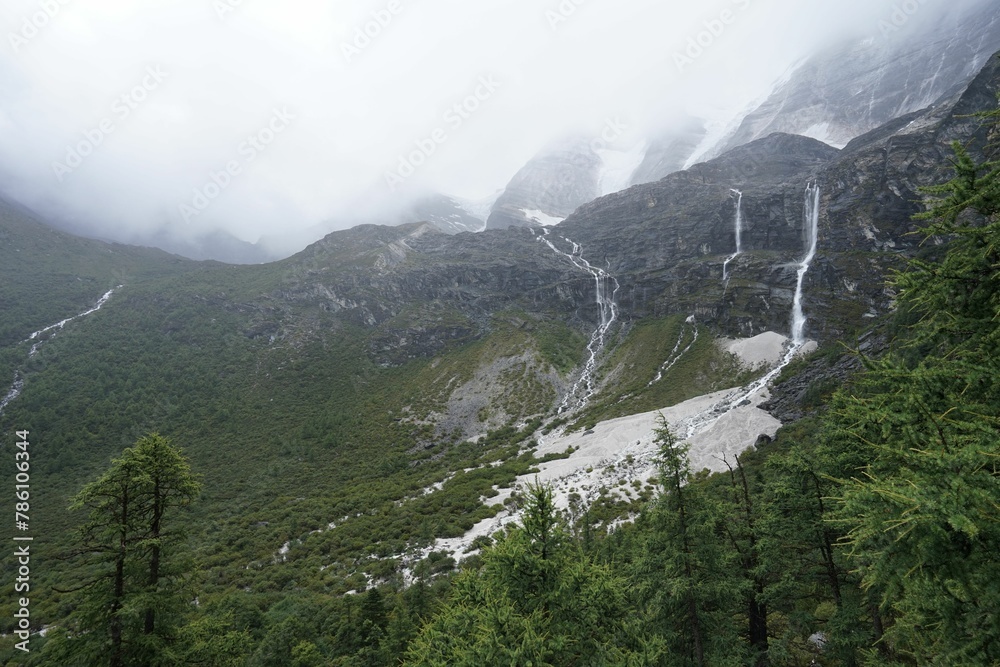 Obraz premium Scenic shot of amazing mountains covered in fog in Daocheng Yading national park, Sichuan, China