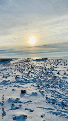 Vertical shot of a rocky beach covered by snow during a winter sunset