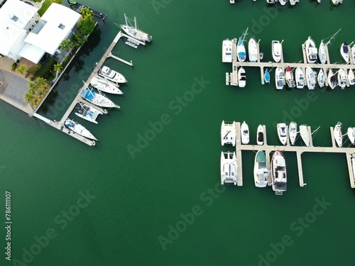 High-angle shot of lots of white boats parked in their places next to a seaside house in an open sea