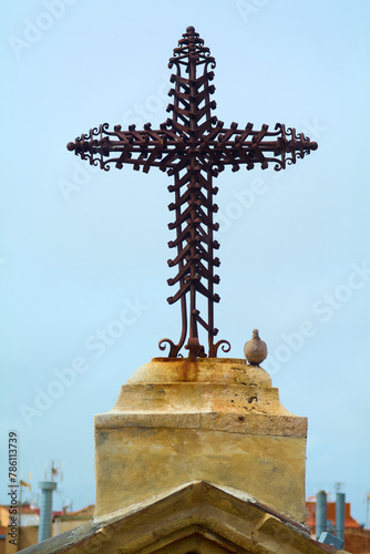 Canvas Print Dove perched next to an ornate metal cross, located atop a Christian church, under a cloudless sky