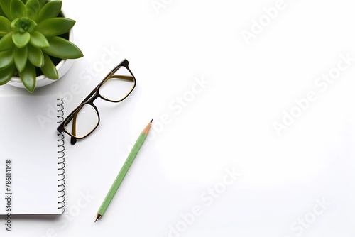 an open notepad with glasses and a green plant on top photo