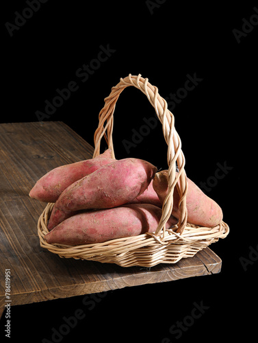 A basket of sweet potatoes on a wooden table photo