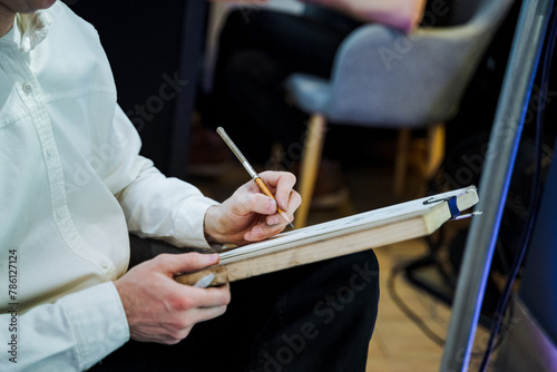 A man is holding a pencil and paper with his hand