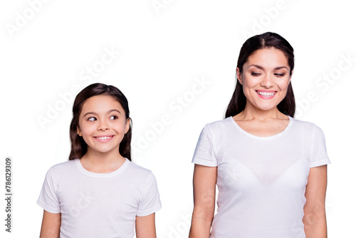Close up photo amazing pretty two people brown haired mum and small daughter standing straight looking side each other cunning wearing white t-shirts isolated on bright blue background