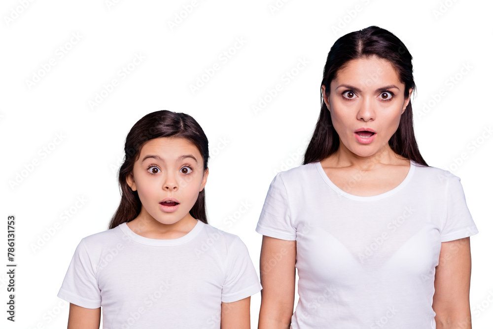 Close up photo pretty two people brown haired mum small little daughter eyes mouth opened frightened by children clothes prices wearing white t-shirts isolated bright blue background Close up photo pretty two people brown haired mum small little daughter eyes mouth opened frightened by children clothes prices wearing white t-shirts isolated bright blue background