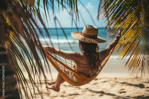 rear view of woman swinging in hammock on the tropical beach © Di Studio
