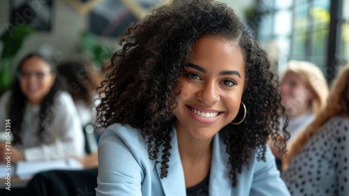 smiling business woman sitting at a table with a group of young people in an office