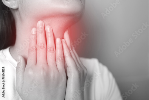sore throat pain. Closeup of young woman sick holding her inflamed throat using hands to touch the ill neck in blue shirt on gray background.