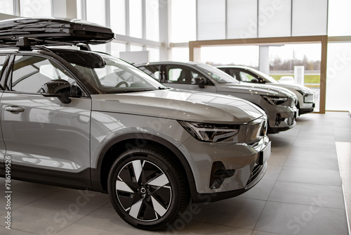 Side view of new SUVs car parked in row indoors modern light dealership showroom.