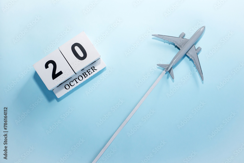 October calendar with number  20. Top view of a calendar with a flying passenger plane. Scheduler. Travel concept. Copy space.