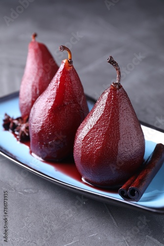 Tasty red wine poached pears and spices on grey table, closeup