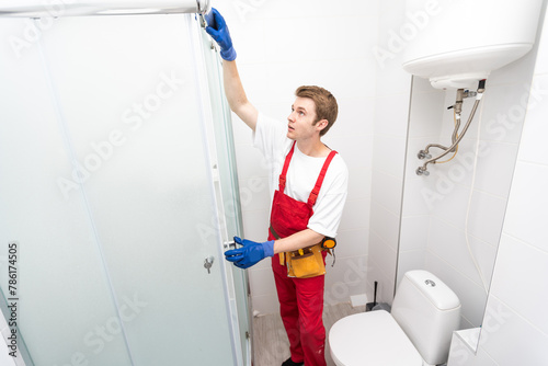 Plumber installing a shower cabin in bathroom