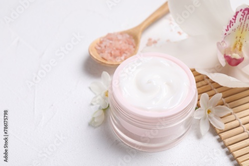 Beautiful spa composition with cosmetic products and flowers on white table. Space for text