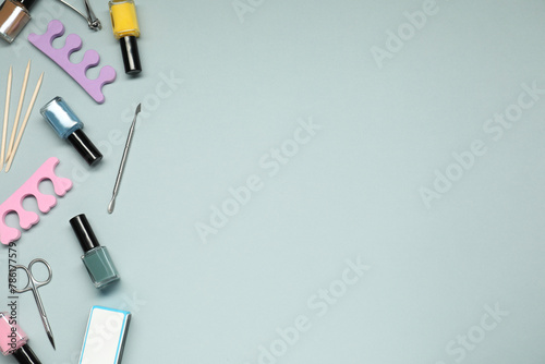 Nail polishes and set of pedicure tools on grey background, flat lay. Space for text