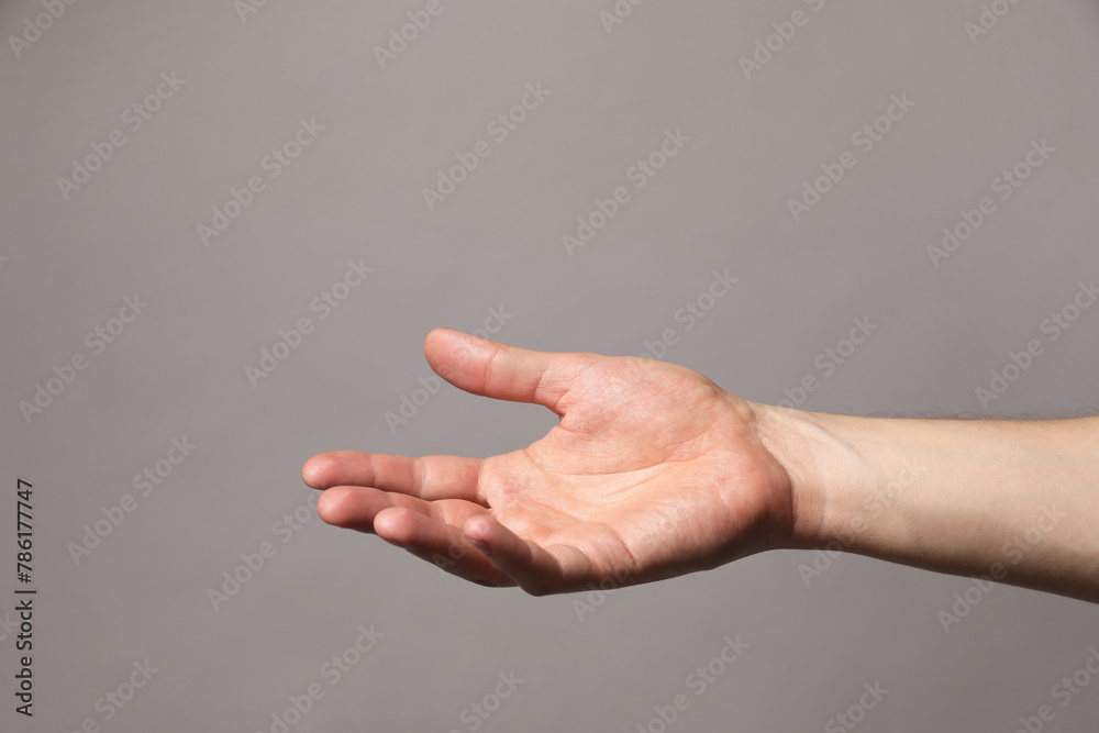 Man holding something in hand on grey background, closeup. Space for text Man holding something in hand on grey background, closeup. Space for text