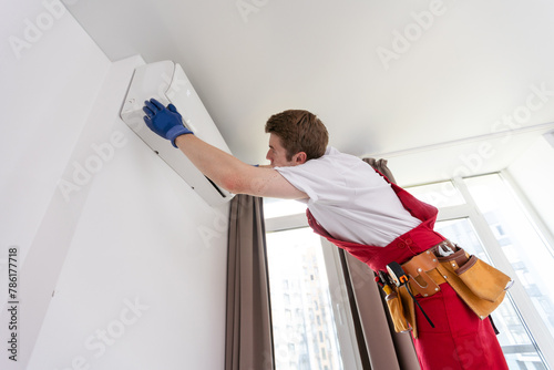 Professional technician maintaining modern air conditioner indoors.