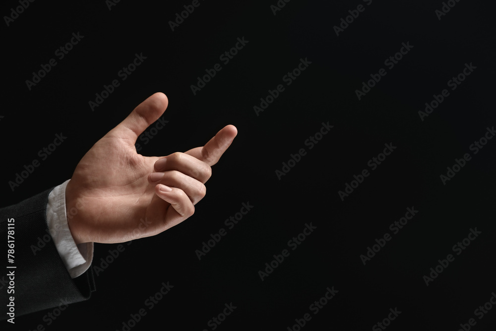 Man holding something in hand on black background, closeup. Space for text Man holding something in hand on black background, closeup. Space for text