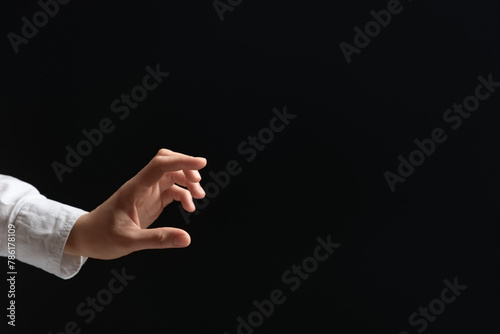 Woman holding something in hand on black background, closeup. Space for text