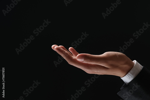 Man holding something in hand on black background, closeup. Space for text