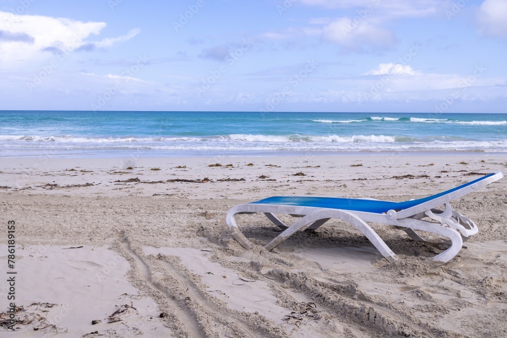The beautiful sandy beach on a summers sunny day showing a blue and white sun lounger on the beach taken on a beach in the town of Varadero in Cuba The beautiful sandy beach on a summers sunny day showing a blue and white sun lounger on the beach taken on a beach in the town of Varadero in Cuba