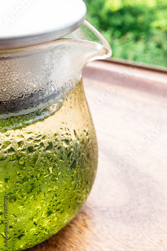 汗をかいたガラスのポットに入った冷たい水出し緑茶
